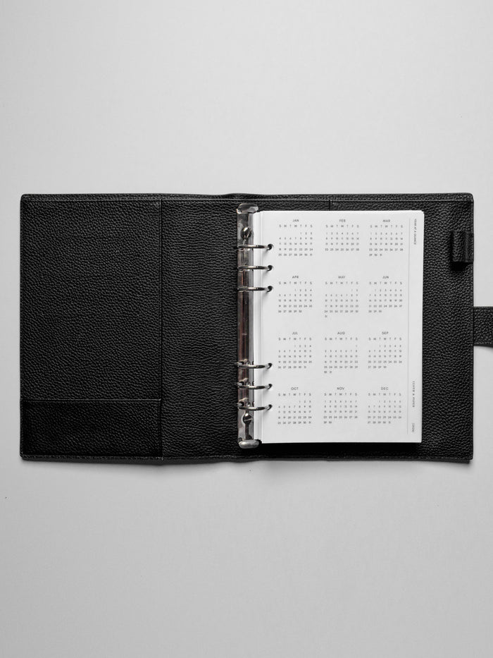 The 2026 Year At A Glance Planner Dashboard in a black leather ring-bound planner.