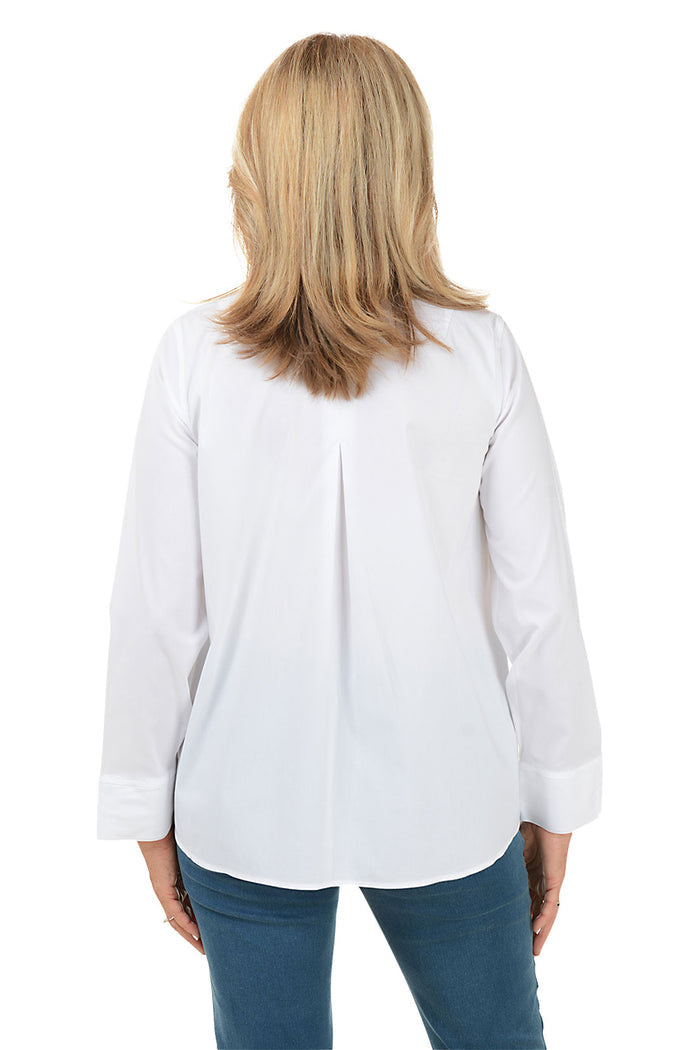 A back shot of a model wearing a white long sleeve blouse with a foldover collar, center front seam, and center back pleat. The blouse has long sleeves with 3-inch slits on cuffs and a high-low hemline with a 3-inch center slit.