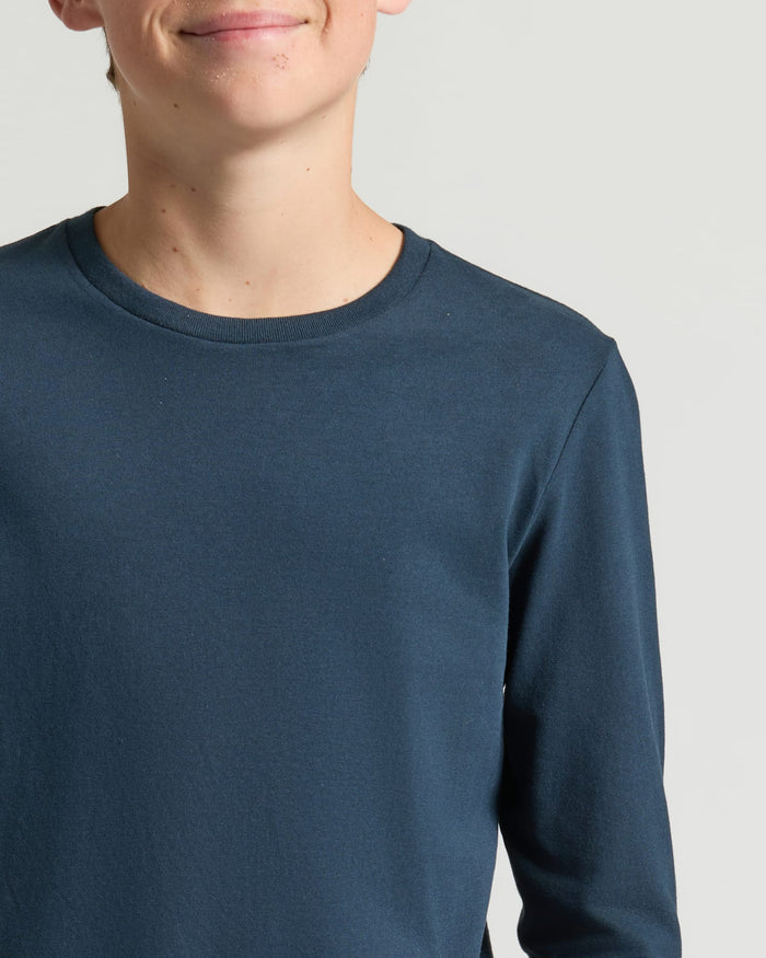 Boy wearing Boys' Navy Classic Long Sleeve Curved Hem Crew, faint smile visible.