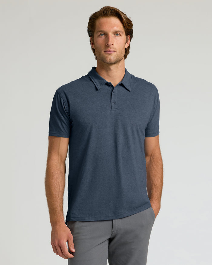 Man wearing a navy blue polo shirt against a light gray background