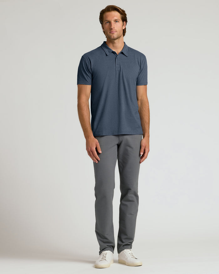 Man wearing a blue polo shirt and gray pants on a light gray background