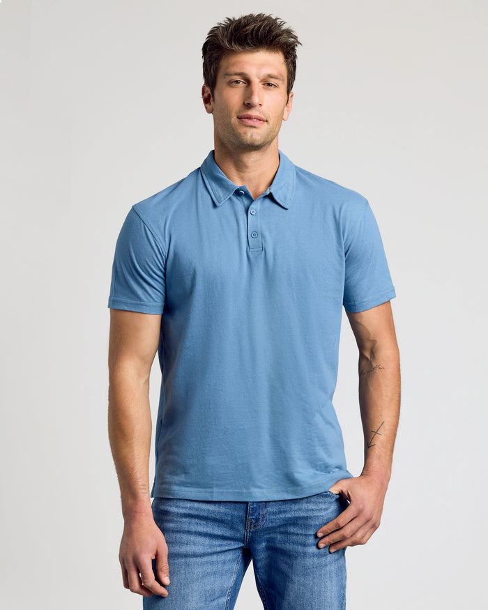 Man wearing a light blue polo shirt paired with blue jeans modeling the Variety Polos 7-Pack, showcasing a classic men's basics style with a comfortable fit.