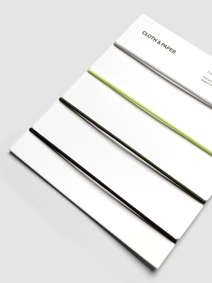 Packaging close-up showing orange, grey, green, and black elastic bands.