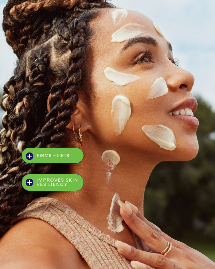Woman with braided hair applying Firm Believer Goji Stem Cell + Pomegranate Smoothing Neck + Face Cream | Three Ships on her face and neck, showcasing skincare benefits that firm and lift while improving skin resiliency.