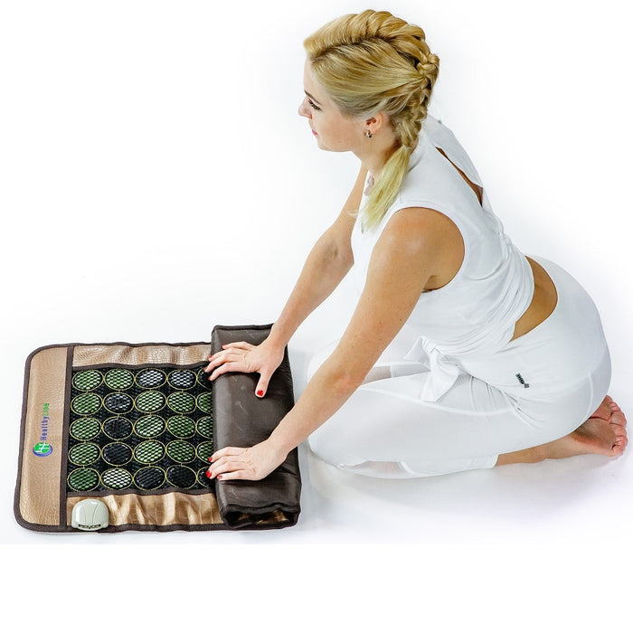 Woman in white attire unrolling a Mesh JT Pad Medium 3220 Soft InfraMat Pro® | HealthyLine on a white surface for wellness and body care use.