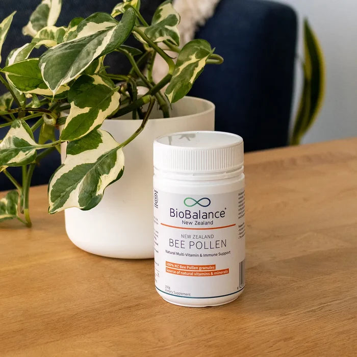 BioBalance New Zealand bee pollen supplement on a wooden table with a plant in the background.