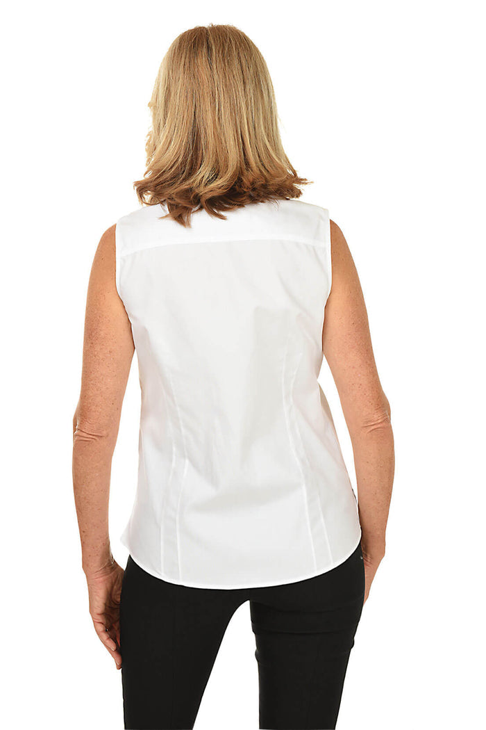 A back shot of a model sleeveless white blouse with a classic foldover collar, full button-front, and a covered placket. It has a rounded hemline with a 3-inch side slit on the hemline.