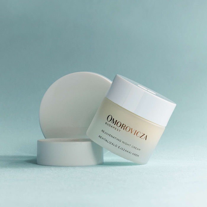 Rejuvenating Night Cream | Omorovicza in a frosted jar with a white lid, displayed on a soft blue background, highlighting luxury skincare for nighttime rejuvenation.