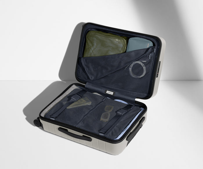The Bigger Carry-On suitcase in Cloud Gray shown open on its side and packed with Away's packing organizers to show capacity and the interior compression system, designed to help you pack more in
// 
Our signature interior compression system allows you to stay more organized. Paired with The Insider Packing Cubes.