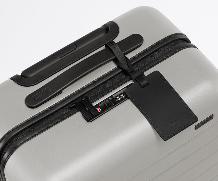 The Bigger Carry-On suitcase in Cloud Gray shown shown from above highlighting TSA-approved combination lock and recycled leather luggage tag
//
All of our suitcases come with a leather luggage tag. Add up to three letters to personalize yours and stand out at the baggage claim.