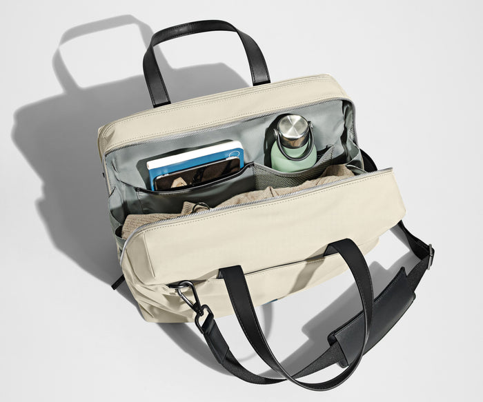 Main compartment packed with a light sweater, notebook, tablet, and water bottle. The detachable shoulder strap is clipped onto the bag.
// The Everywhere Bag features a detachable padded shoulder strap.