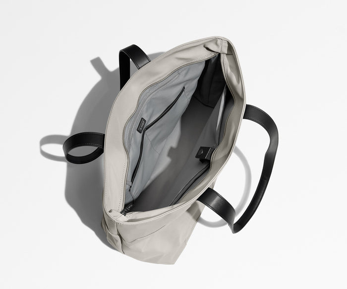 Unzipped and unpacked Everywhere Tote bag, showing the interior zip pockets, slip pockets, and laptop pocket