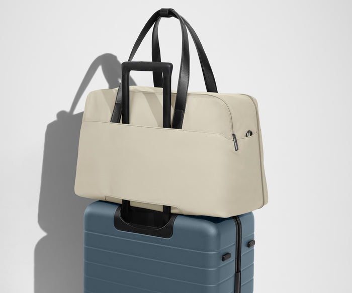 Weekender sitting on an Away Large suitcase, using the trolley sleeve pass-through
// Our duffles are designed with a trolley sleeve that slides onto your suitcase to keep it in place while you’re on the move. Paired with The Large.