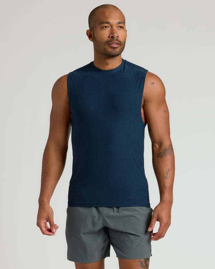 Man in Limited Sleeveless Active Muscle Tee, showcasing tattoos and relaxed posture.