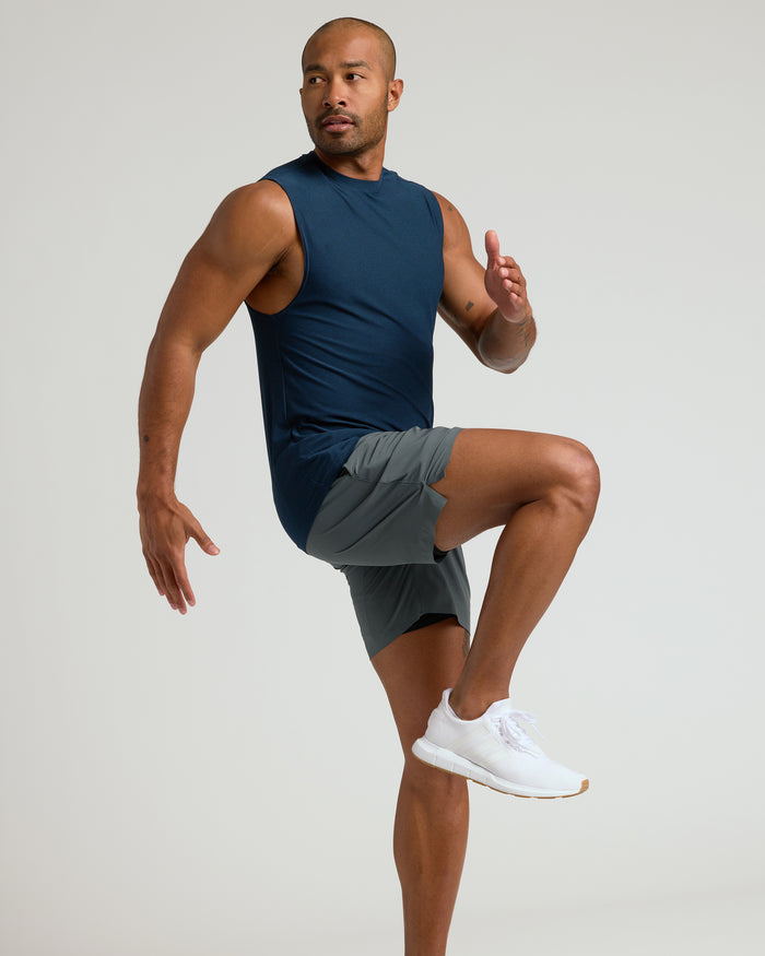 Man in Sleeveless Active Muscle Tee performing high-knee exercise.