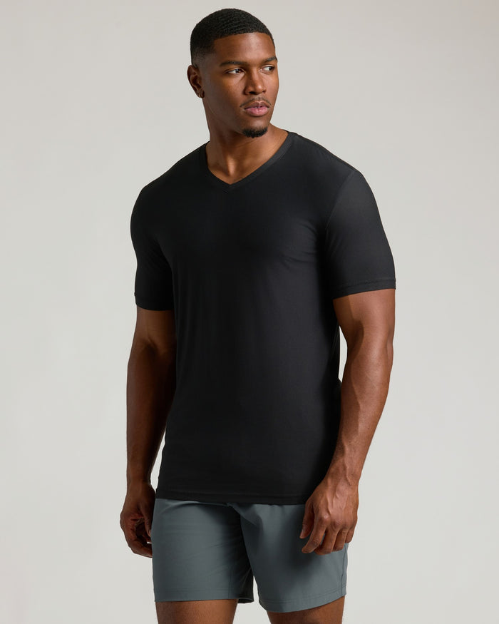 Man wearing a black t-shirt and gray shorts on a plain background