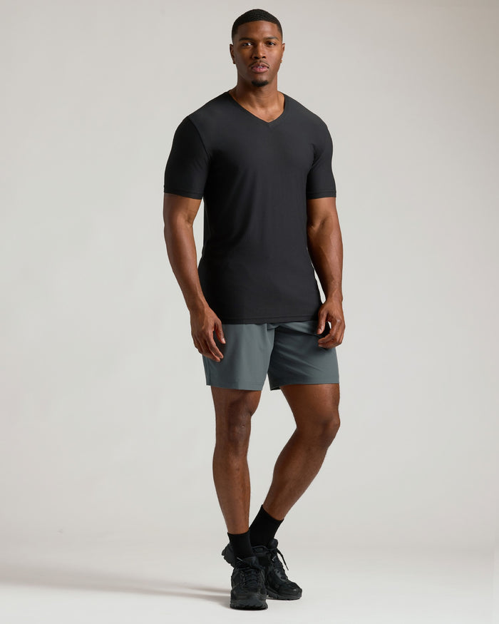Man wearing a black t-shirt and gray shorts on a plain background