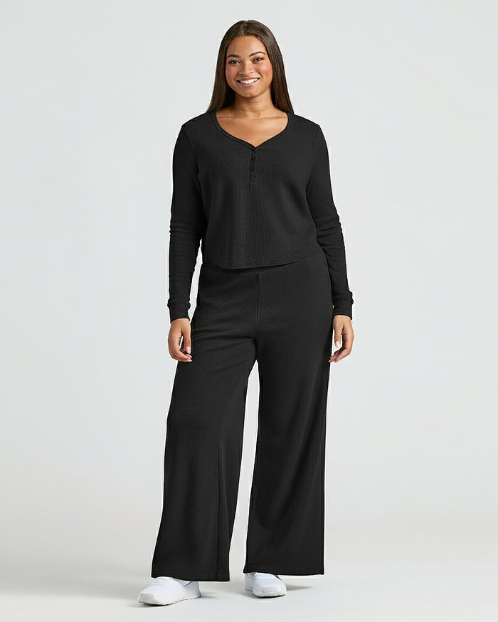 Woman wearing Womens Black Waffle Long Sleeve Boxy Henley lounge set, smiling.
