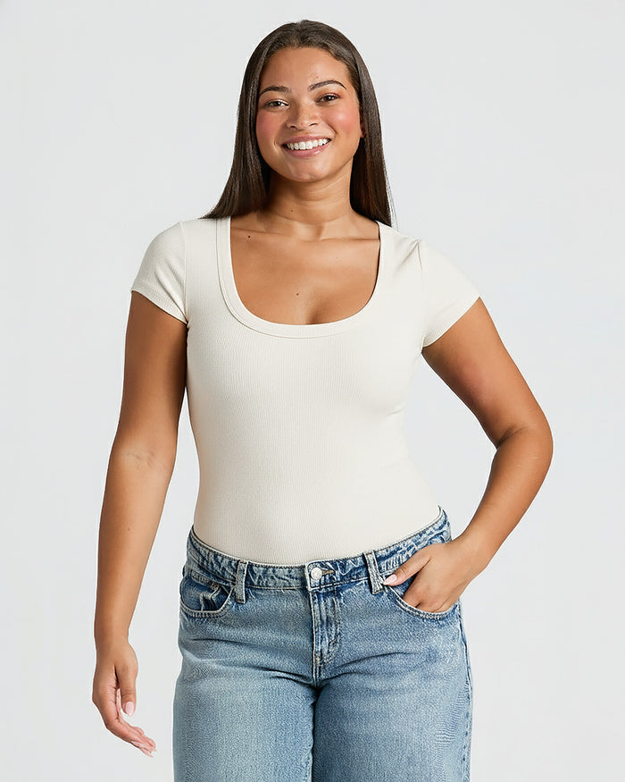 Woman wearing a white t-shirt and blue jeans against a plain background. MODEL_INFO: Jade is 5'9", wearing a size L